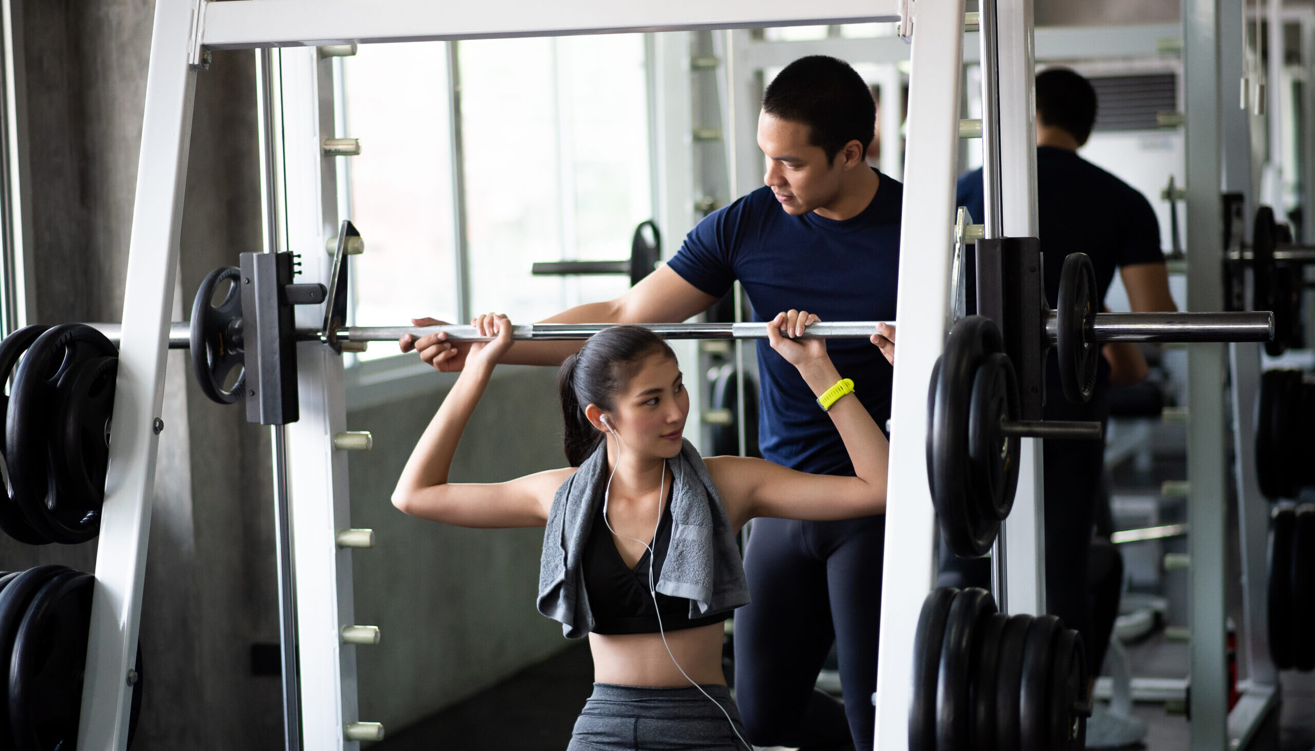 young woman with fitness instructor lifting barbell gym (1)